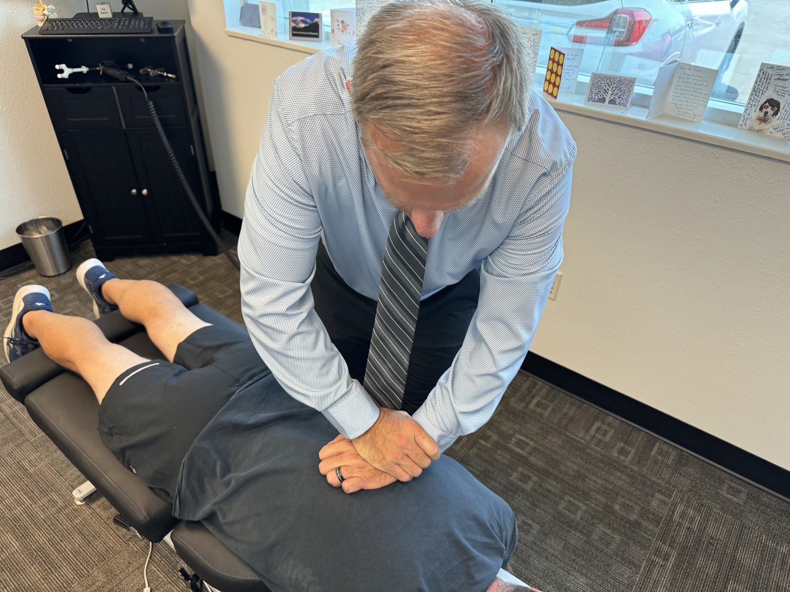Chiropractor examining patient's lower back with hands-on palpation during office visit