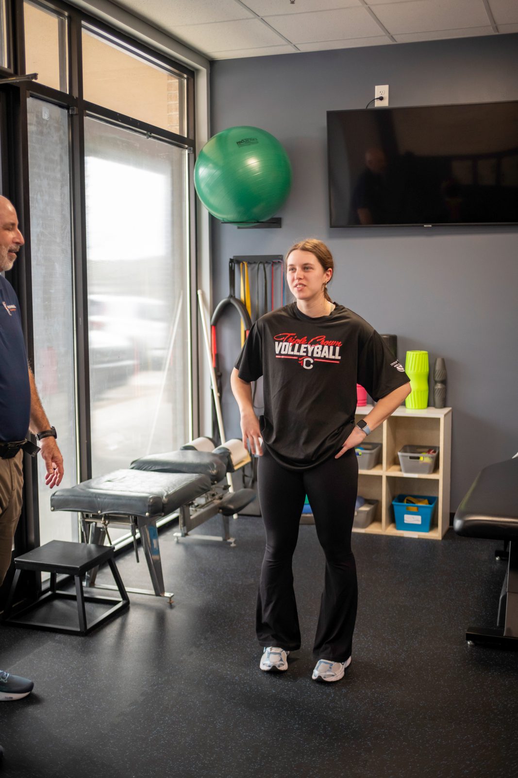 Sports Chiropractic Nashville: Care Built for Athletes 1 Young athlete in volleyball shirt standing in clinic room with staff member and exercise equipment